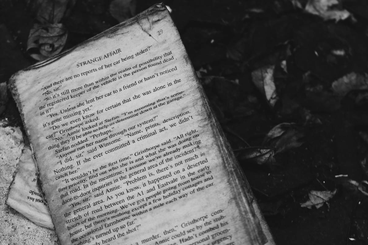 A weathered stack of good zombie apocalypse books beside a tactical flashlight and map